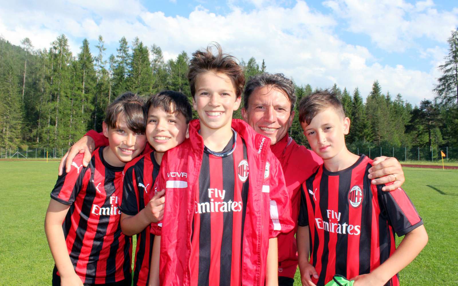L'ancien footballeur Stefano Eranio embrasse quatre enfants qu'il entraîne pendant l'école de football d'été de l'AC Milan