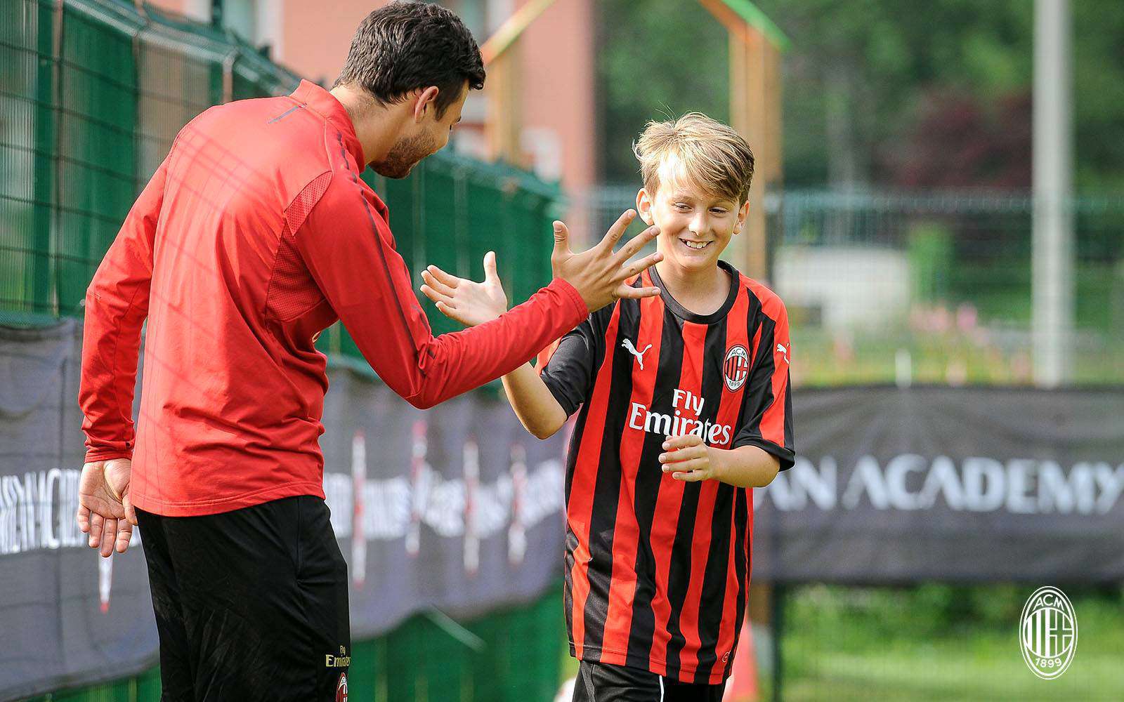 A coach of the AC Milan Academy Camp staff congratulates the young footballer